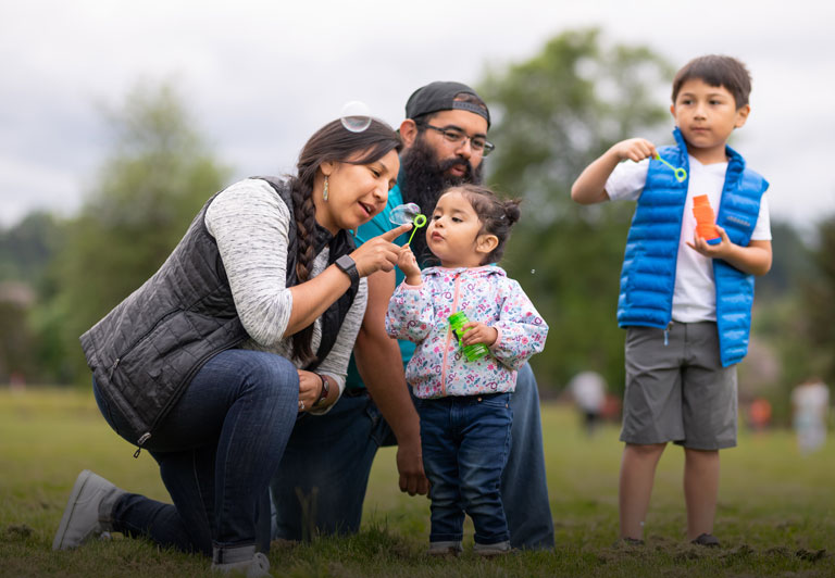 Native American community: a family enjoys the day outdoors, blowing bubbles.
