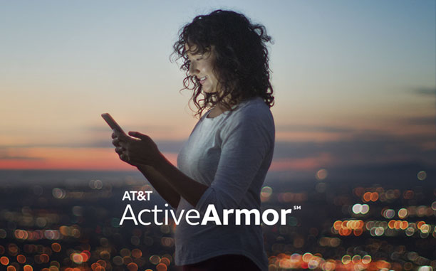 Woman looking at her cell phone with a cityscape far in the background, with the text AT&T ActiveArmor displayed