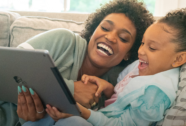 Woman and child laughing while looking at tablet screen