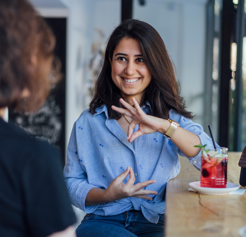 Woman smiles while using sign language.