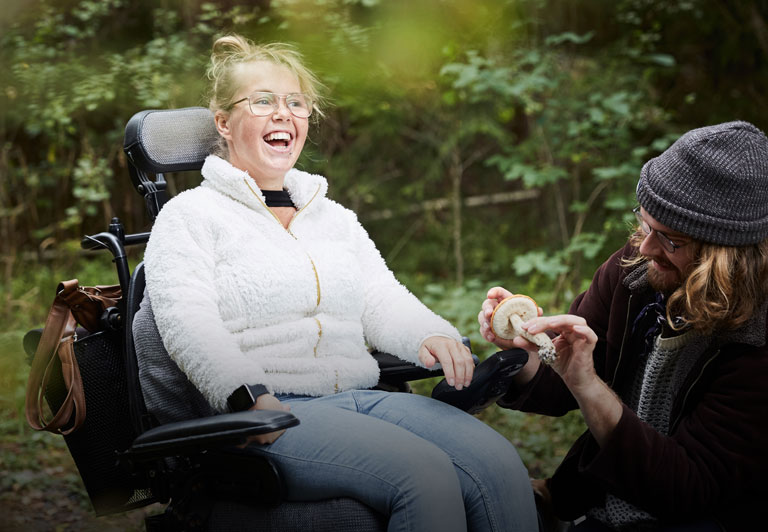 People with Disabilities: woman in wheelchair smiles while sitting with a friend. 