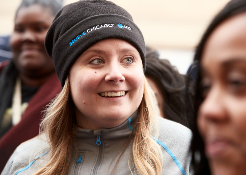 An AT&T employee smiles while wearing an AT&T Believes winter hat.