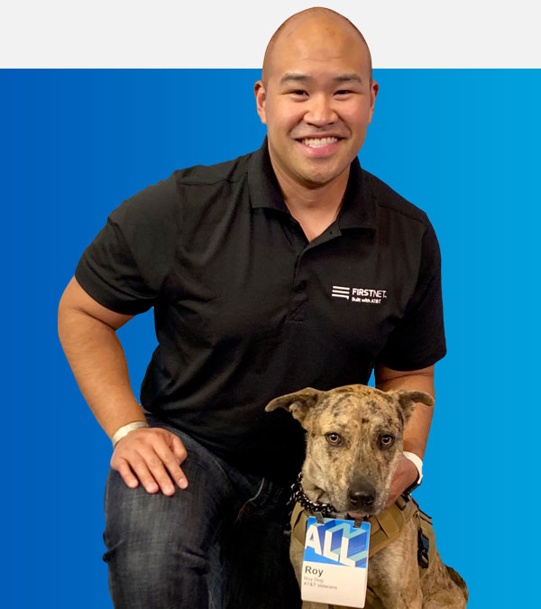 AT&T employee and veteran Scott Mendoza sits smiling with his service dog, Roy.