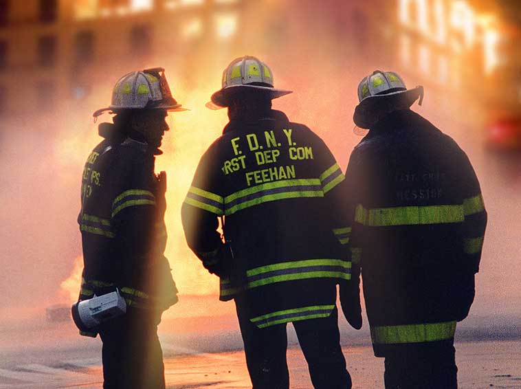 Firefighters standing in front of a building on fire