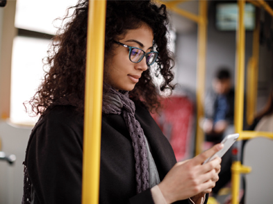 A woman sits on a bus looking at her smartphone