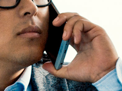 A man wearing glasses speaks on a cell phone