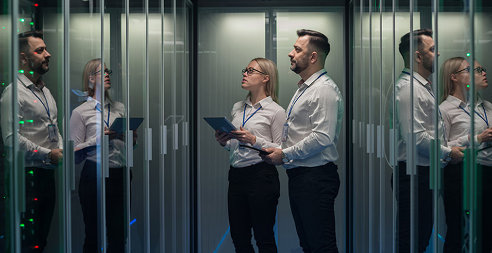 Two people look on at servers in a data center