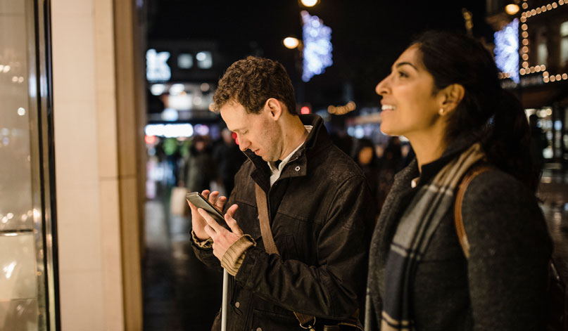 Man looks at smartphone while woman looks ahead