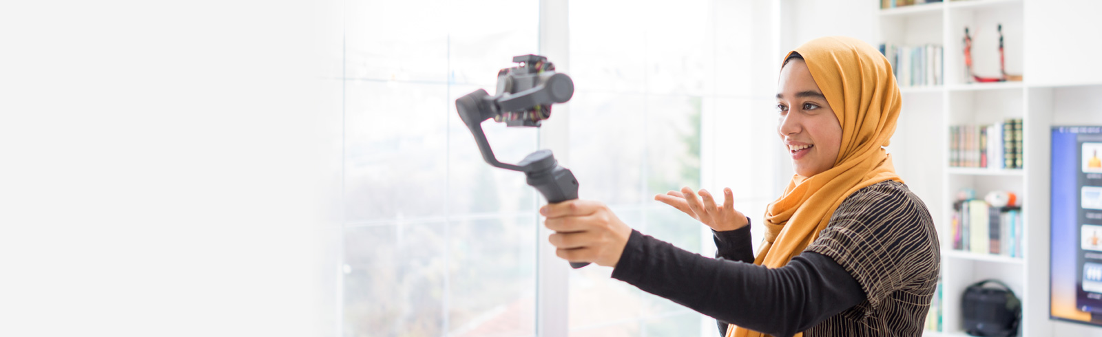 A woman holding a camera stabilizer speakers into the camera