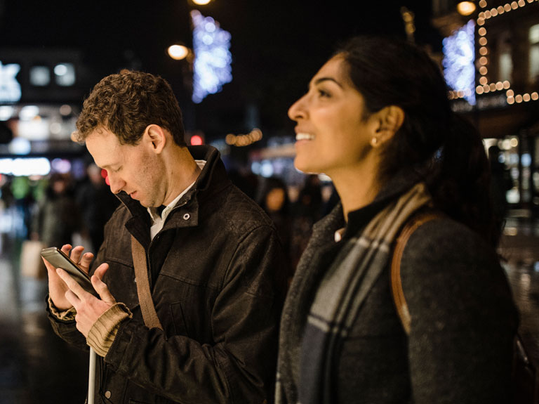 Man looks at smartphone while woman looks ahead