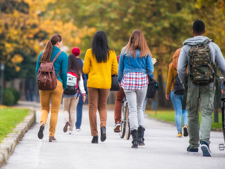 A group of college students walk around campus