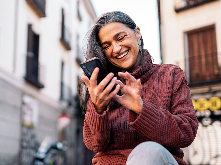A woman smiles while using her smartphone