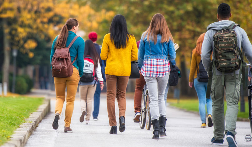A group of college students walk around campus