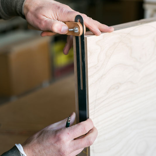 A woodworker measuring a piece of plywood