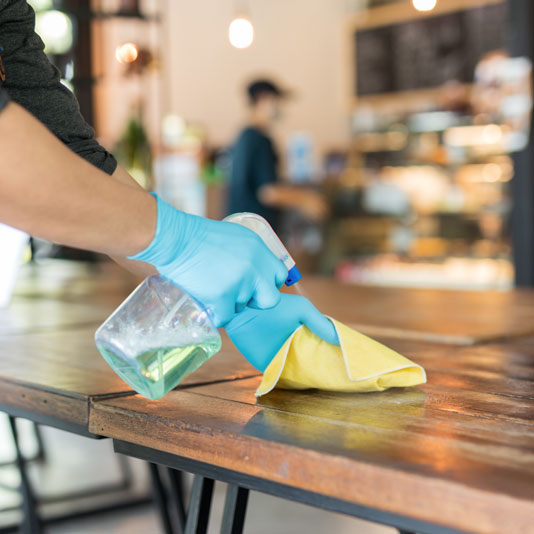 A restaurant worker cleaning a dining surface