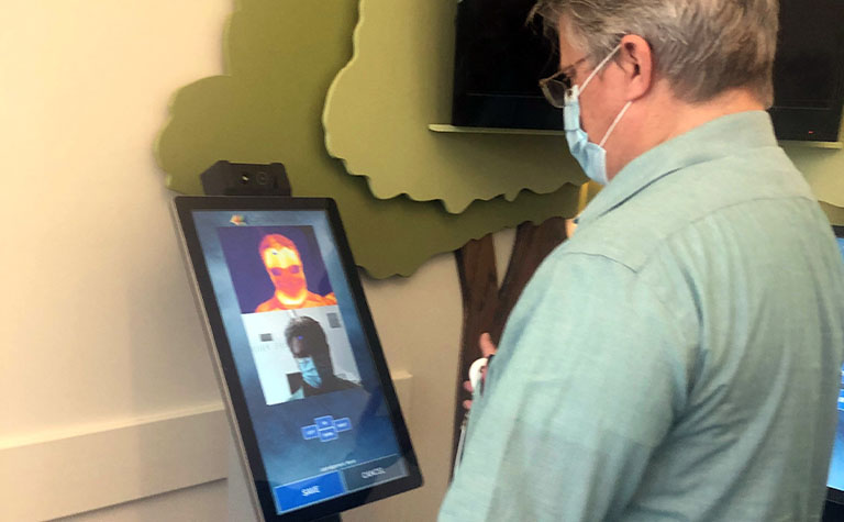 A patient uses a temperature screening kiosk using AT&T technology
