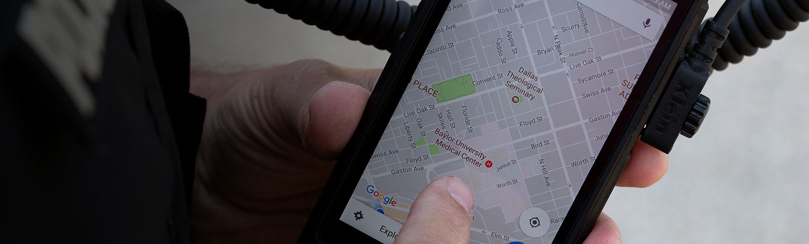 Hands holding a cell phone while reviewing “Baylor University Medical Center” on a map on the screen 