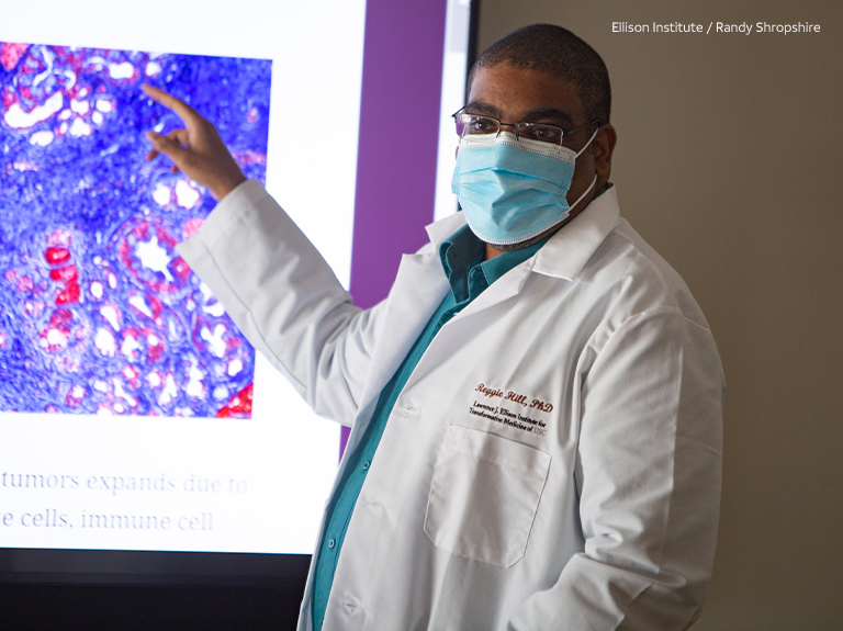 Male researcher presents research from board at Ellison Institute. 