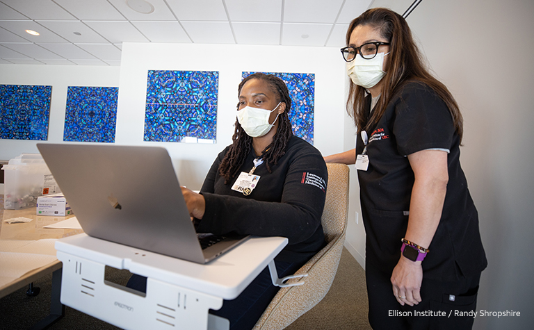 Two female medical professionals work on laptop at Ellison Institute. 