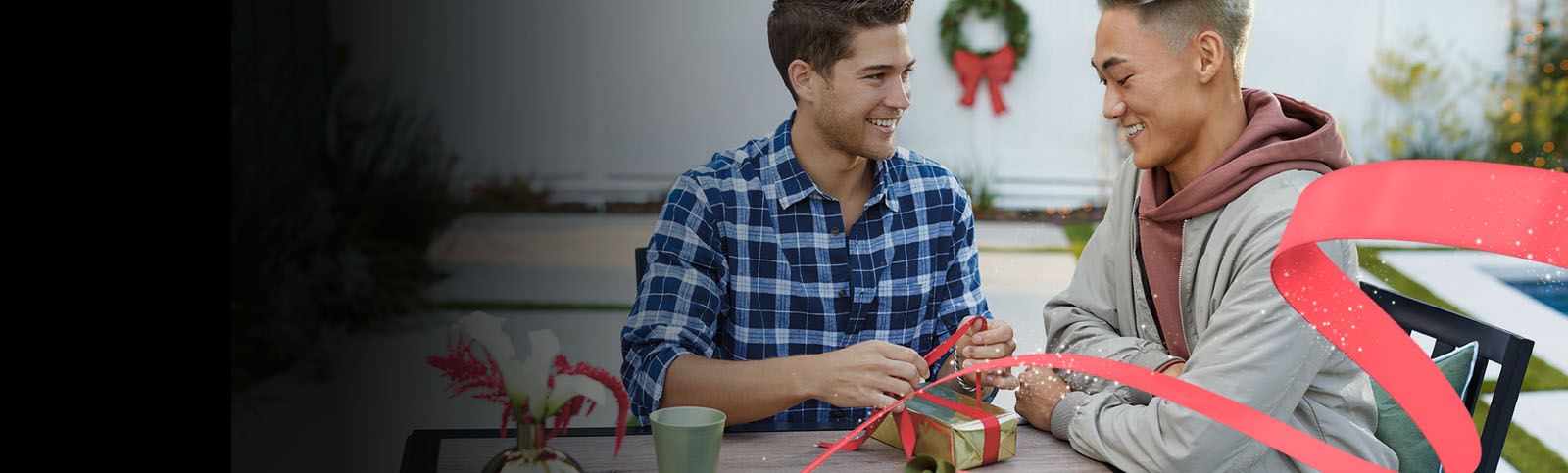 Two men smile and exchange presents outside