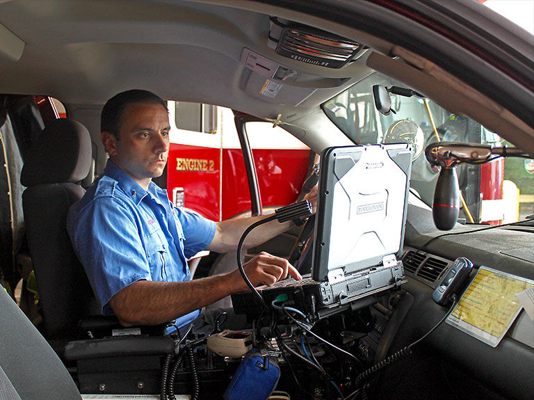 EMT sits in emergency vehicle while checking a computer