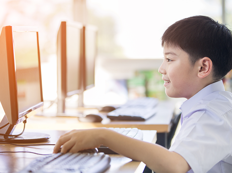 Young boy smiling using computer.