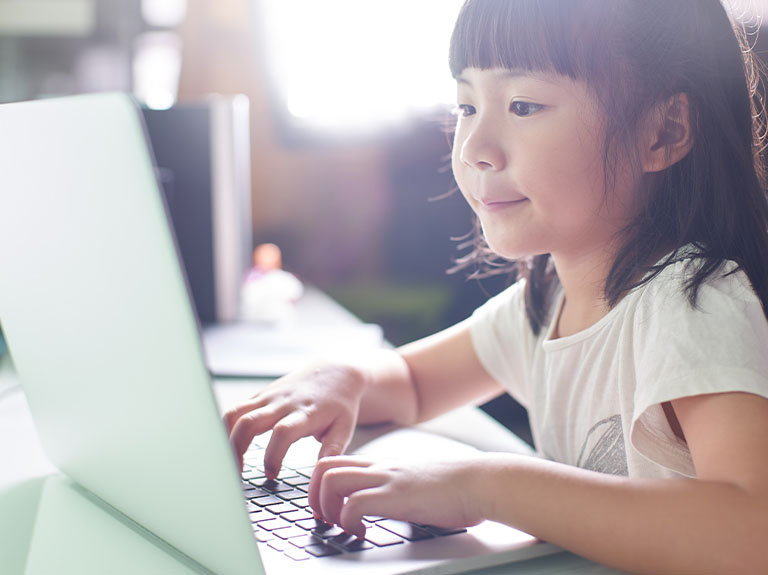 Child seated at laptop.
