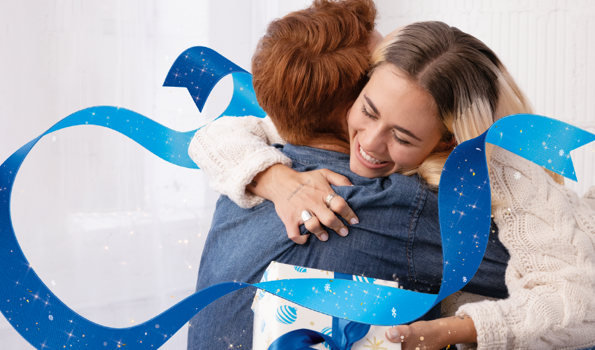 Woman and man hugging, smiling from receiving AT&T wrapped gift.