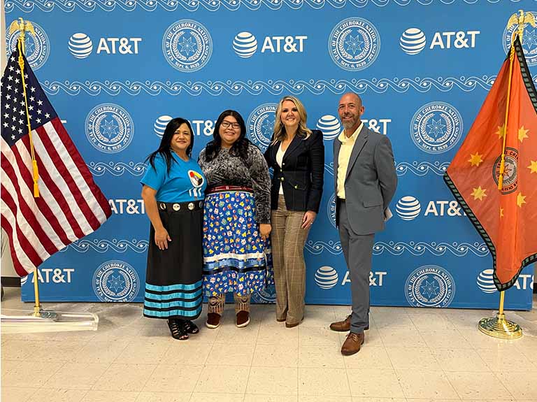 Left to right: AT&T employees Rachel Salinas, Angel Benally, Erin Scarborough and Joshua Davis pose for a group photo in front of a backdrop at the opening of the Cherokee Nation AT&T Connected Learning Center® in Catoosa, OK.