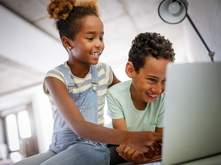 Happy children doing online learning on laptop.