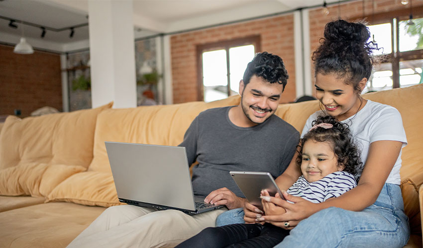 A young family uses various digital devices while connected to Wi-Fii at home.